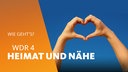 Zwei Hände formen ein Herz vor dunkelblauem Himmel