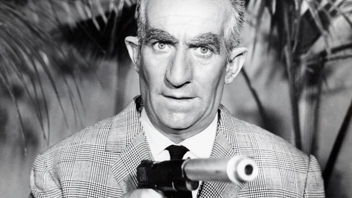 Szene aus dem Spielfilm "Fantomas": Inspektor Juve (Louis de Funès) hält einen Revolver in der Hand