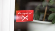 Eine Terassentür mit einem roten Aufkleber, der darauf hinweist, dass das Grundstück alarmgesichert ist