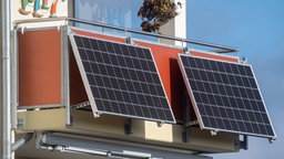 Solarmodule für ein Balkonkraftwerk hängen an einem Balkon