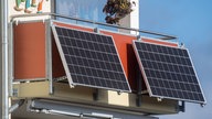 Solarmodule für ein Balkonkraftwerk hängen an einem Balkon