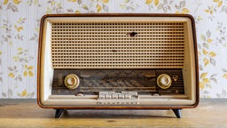 Ein altes Blaupunkt Radio Granada steht auf einer Kommode vor einer Blümchentapete