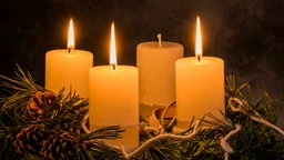 Ein Adventskranz, auf dem drei Kerzen brennen.