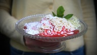 Eine angerichtete Glasschüssel mit Spaghettieis und Erdbeersauce