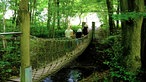 Bad Wünnenberg: Drei Personen überqueren eine Hängebrücke über einen Bach