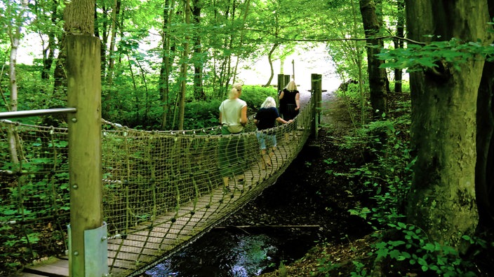 Bad Wünnenberg: Drei Personen überqueren eine Hängebrücke über einen Bach