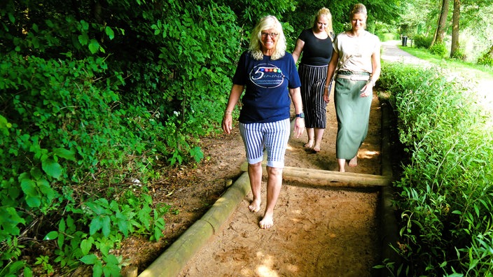 Bad Wünnenberg: Drei Kneipp-Wanderinnen barfuß auf einem Sandweg
