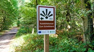 Ein Hinweis-Wanderschild Schild am Waldwegsrand mit der Aufschrift "Aussichtskanzel Zum Schießstand"