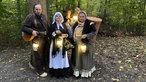 Verkleidete Darsteller mit Laternen im Wald