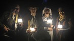 Vier verkleidete Darsteller mit Laternen in Dunkeln.