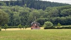 Ein einsames Häuschen steht auf einem Feld am Waldrand