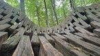 Eine Nestschaukel aus Holz hängt im Wald des Nieheimer Kunstpfads. 