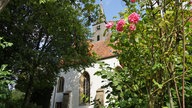 Blick auf eine Kirche von unten betrachtet, gesäumt von Rosenranken