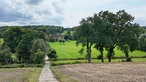 Weiter Blick auf Landschaft mit Bäumen und einem Gutsbauernhof