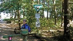 Westruper Heide: Carola de Marco vom Naturschutzbund steht im Wald vor Hinweis-Schildern
