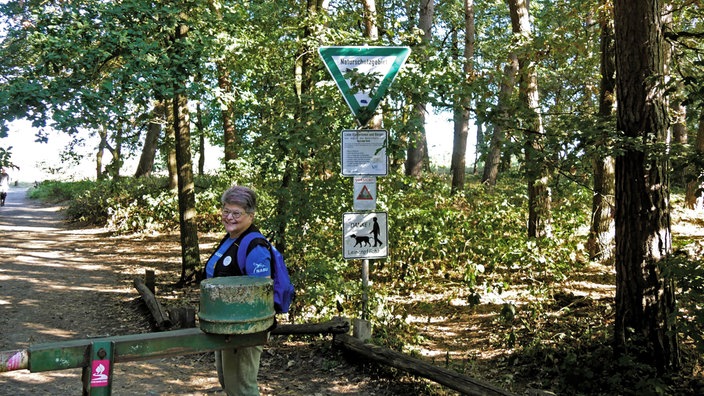 Westruper Heide: Carola de Marco vom Naturschutzbund steht im Wald vor Hinweis-Schildern