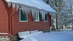 Eiszapfen am Dach eines Hauses mitten im Wald am Wanderweg bei Hoheleye