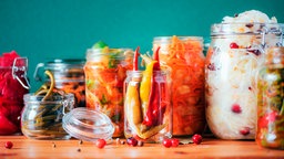 Verschiedenes fermentiertes Gemüse in Einmachgläsern: Karotten, Kimchi, Beete, Sauerkraut und saure Gurken.