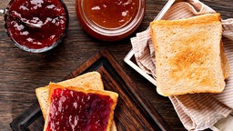 Rote Konfitüren in Gläsern und Toastbroat-Scheiben
