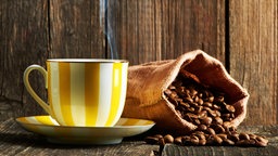 Eine Tasse Kaffe neben einem Sack mit Kaffeebohnen