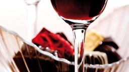 Ein Glas Portwein, im Hintergrund ein Korb mit Pralinen. 