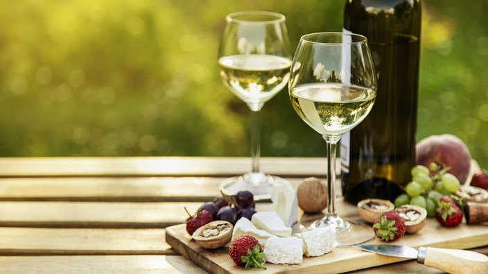 Weißwein und Käseplatte für ein Abendessen im Freien im Garten.
