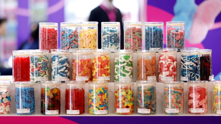 Süßigkeiten, in Gläsern aufgereiht und in mehreren Ebenen präsentiert, auf der Süßwarenmesse.