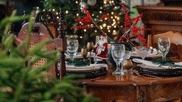 Ein weihnachtlich dekorierter Esstisch, im Hintergrund ein Christbaum 