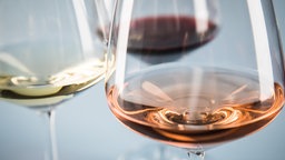 Symbolfoto: Detailaufnahme dreier unterschiedlich befüllter Weingläser: Rosé, Weißwein und Rotwein. 