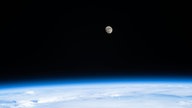 Blick von der ISS auf den Mond, darunter leuchtet blau die Erde