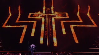 Ein riesiges flammendes Kreuz prägt das Bühnenbild bei einem Madonna-Konzert in Berlin 