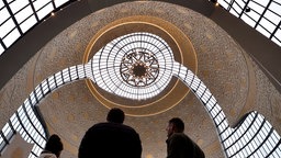 Menschen stehen mit dem Rücken zur Kamera in der Zentralmoschee in Köln, über ihnen spannt sich die weite Kuppel 