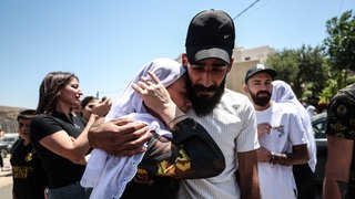 Syrische Drusen am 17.07.2025 in der syrisch-israelischen Grenzregion. Eine weinende Frau und ein traurig blickender junger Mann halten einander im Arm.