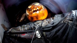 Ein Geist mit Kürbiskopf steht zu Halloween im Vorgarten eines Hauses 