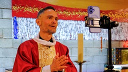 Der französische Priestfluencer Benoit Pouzin blickt in ein Smartphone und nimmt ein TikTok-Video auf