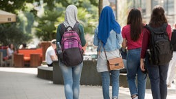 Junge Musliminnnen gehen in einer Innenstadt spazieren.