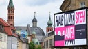 Der Slogan "HAB MUT, STEH AUF!" ist auf dem Residenzplatz vor den Türmen des Kiliansdoms und der Neumünsterkirche zu sehen.