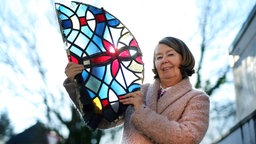 Annette Jansen-Winkeln hält ein kleines Buntglasfenster ins Licht