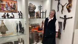 Die Ordensoberin Schwester Angela Maria steht im Überseecontainer der Ausstellung "Räume öffnen" vor Vitrinen mit Artefakten aus der Missionssammlung