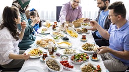 Freunde und Familie am Frühstückstisch während der Feier des Opferfestes