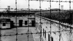 Blick durch Stacheldraht auf die Gebäude des 1941 von der SS errichteten Konzentrationslagers im tschechischen Theresienstadt. 