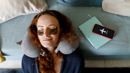 Redhead woman leaning head on sofa with smart phone on airplane mode in living room at home