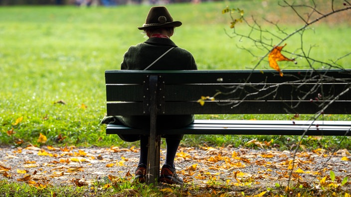 Rentnerin sitzt allein auf einer Parkbank