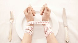 Woman in front of empty plate bound with tape measure