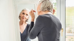 Grey haired senior woman readying herself in mirror