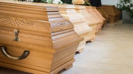 Eine Frau legt einen Kranz auf einen Sarg