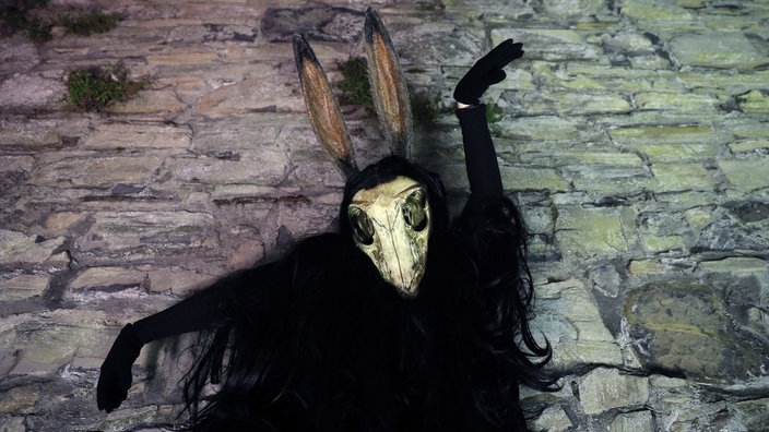 Als "Puca" verkleidet, mit dunkler, wallender Robe und einer Art Hasenschädel-Maske posiert ein Feiernder in Irland an Halloween