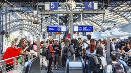 Eine Menschenmenge wartet am Kölner Hauptbahnhof auf ihren Zug