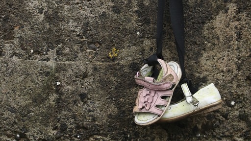 Ein paar Kinderschuhe hängt zum Gedenken an einer Wand nahe dem Kinder-Massengrab in Tuam
