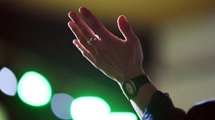 Eine Gottesdienst-Besucherin streckt eine Hand in die Höhe.